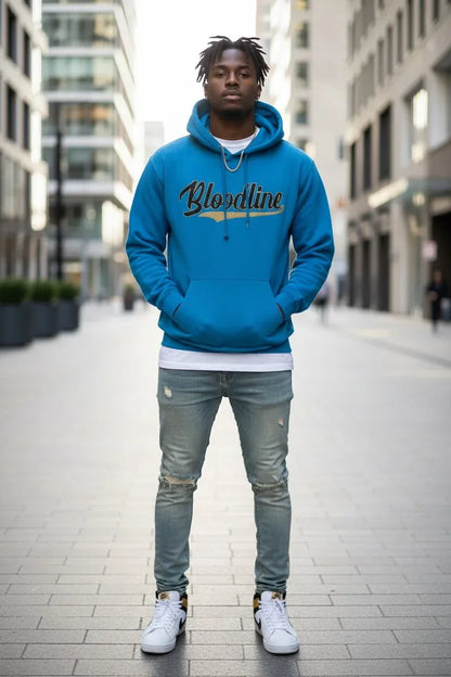 A man standing on a city sidewalk wearing a bright blue hoodie with 'Bloodline' printed across the chest in black and gold, paired with distressed gray jeans and white sneakers.