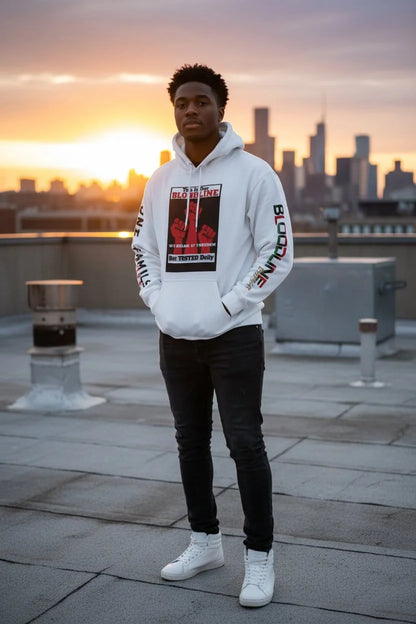 Person wearing a white hoodie with graphic designs on a rooftop with city skyline in the background