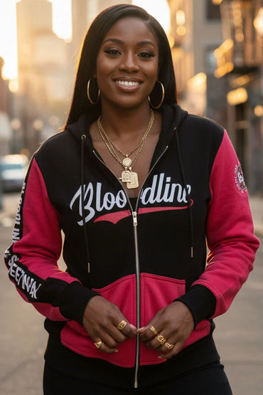 Woman wearing a black and red hoodie with 'Bloodline' text, standing outdoors.