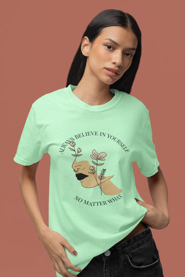 Person wearing a light green t-shirt with a graphic design and text on a brown background
