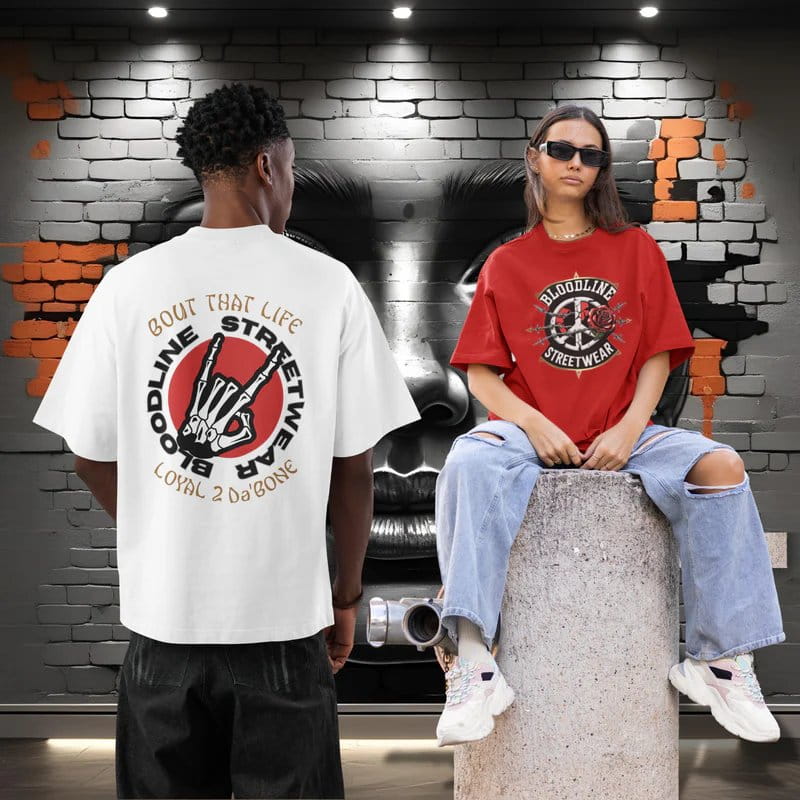 Two people wearing branded t-shirts in front of a brick wall.
