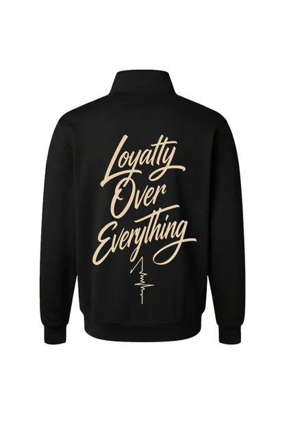 A black long-sleeve quarter-zip jacket shown from the back, featuring the phrase 'Loyalty Over Everything' printed in a large beige cursive font with a small vertical signature graphic below it.