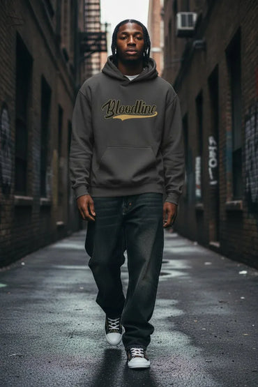 A man wearing a dark gray hoodie with 'Bloodline' printed in gold script across the chest, walking down a wet city alleyway.
