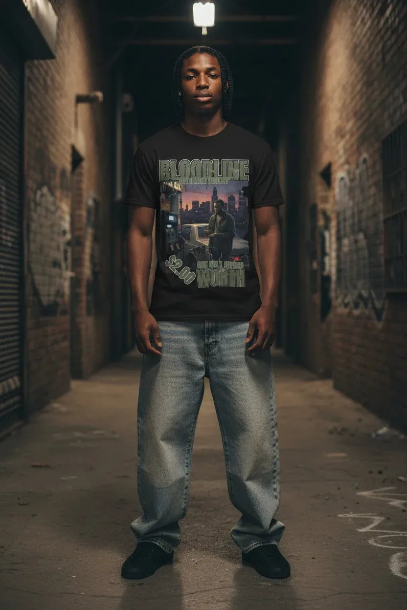 A man stands in a dark urban alley wearing a black graphic t-shirt with 'BLOODLINE' text, paired with light-wash baggy jeans and black shoes.
