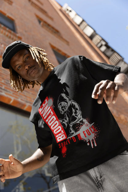 Person wearing a black t-shirt with graphic design and text, standing against an urban background.
