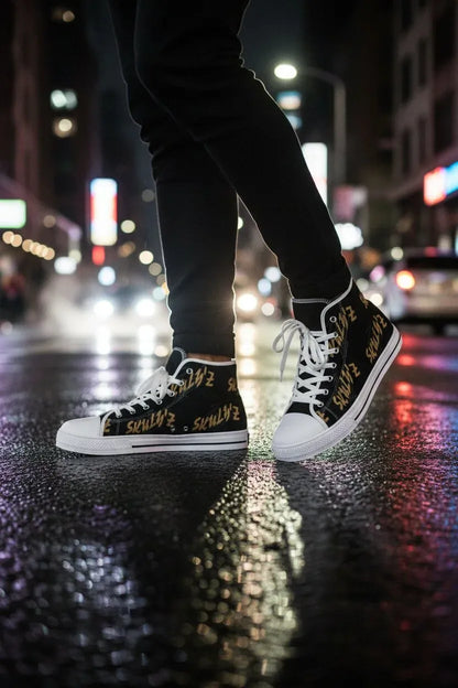A person wearing black high-top sneakers with gold graffiti-style lettering and white laces, standing on a wet city street at night with blurred lights in the background.