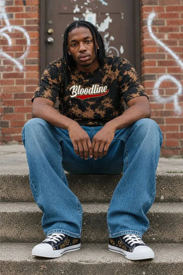 Model seated on steps wearing Bloodline Desert Camo Tee