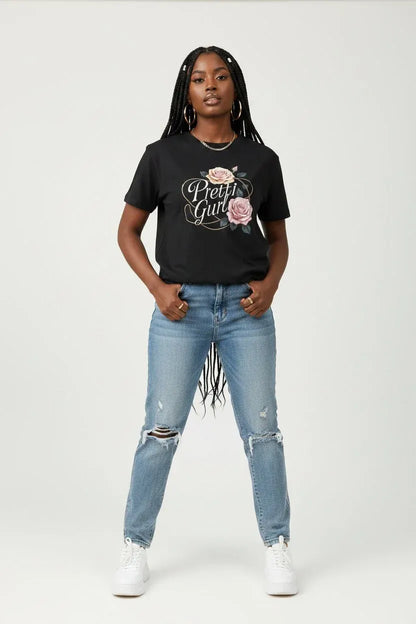 A woman modeling a black graphic t-shirt with 'Pretend Girl' and a rose design, paired with light-wash distressed jeans and white sneakers, against a plain light gray background.