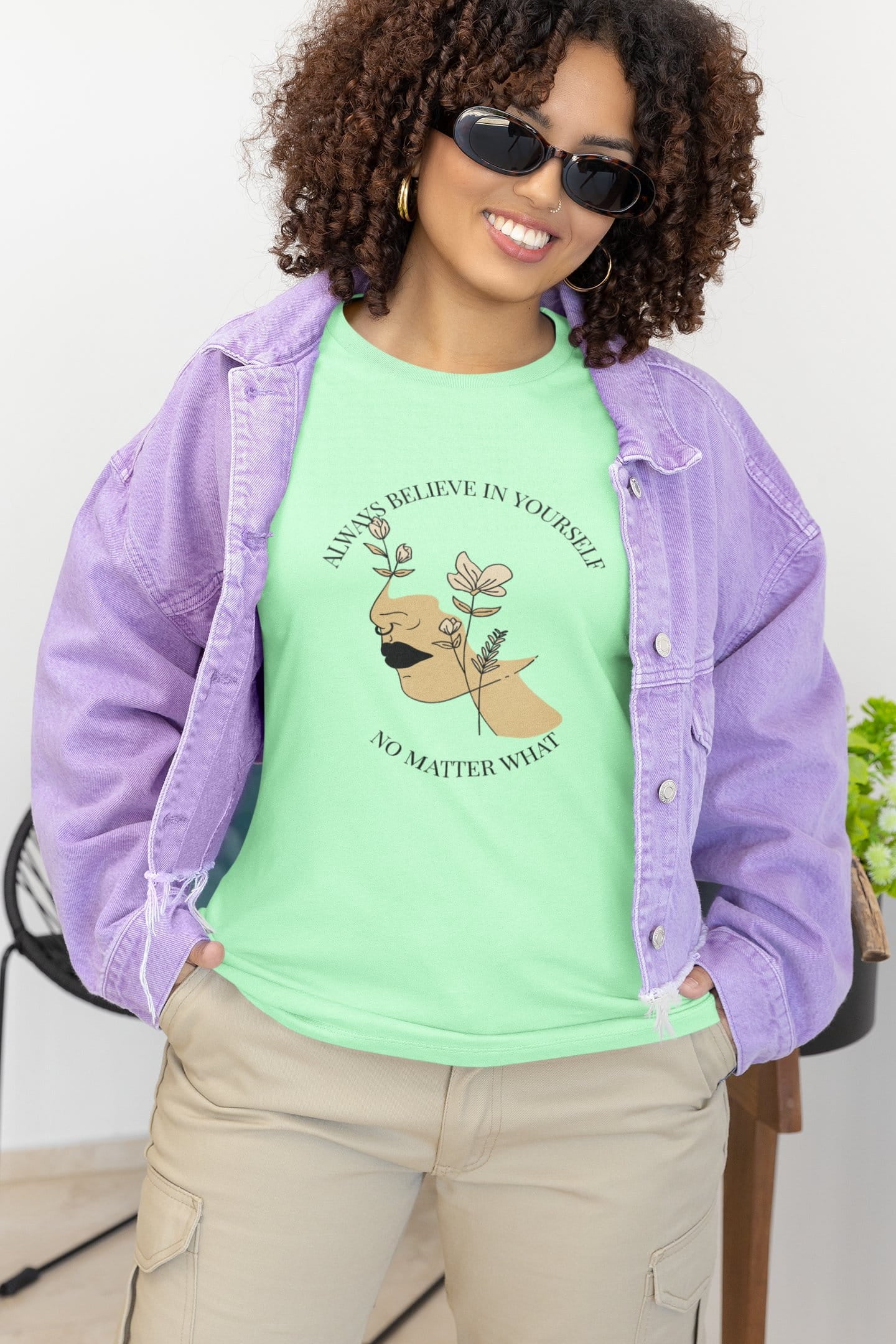 Person wearing a green t-shirt with a graphic and text, paired with a purple jacket.