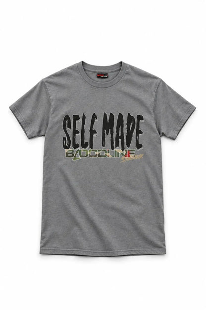 A heather gray crewneck t-shirt featuring a distressed graphic print on the front that reads 'SELF MADE' in black, with 'BY OSOLINE' underneath in a green, yellow, and red patterned design.