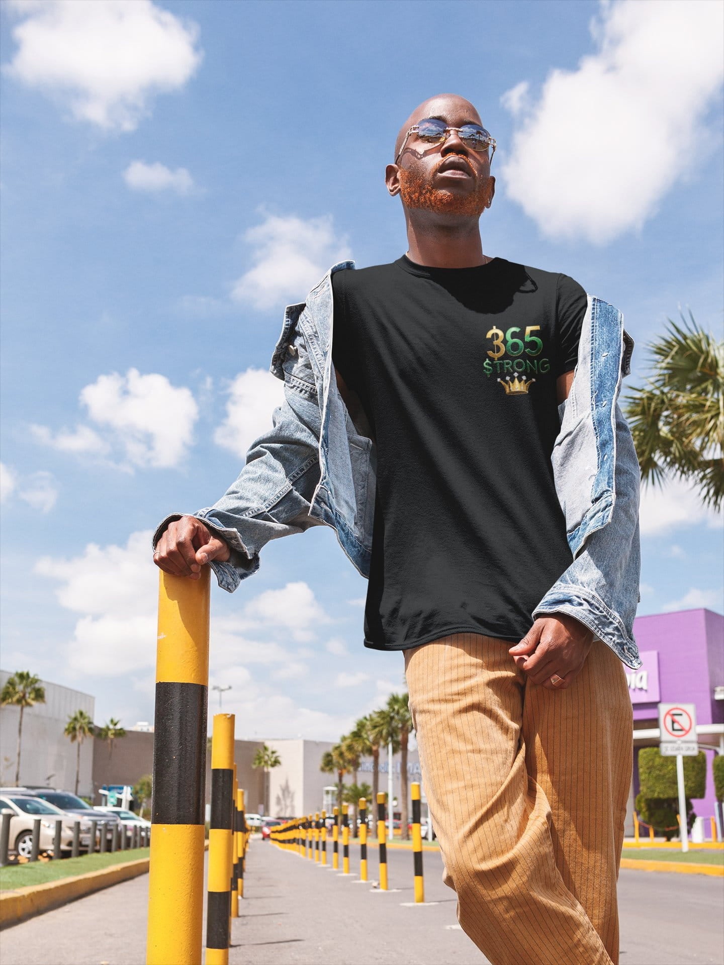 Man wearing a black t-shirt with '365 Strong' text, standing outdoors under a blue sky.